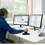 test-automation-analyst-employee-using-software-on-two-screens